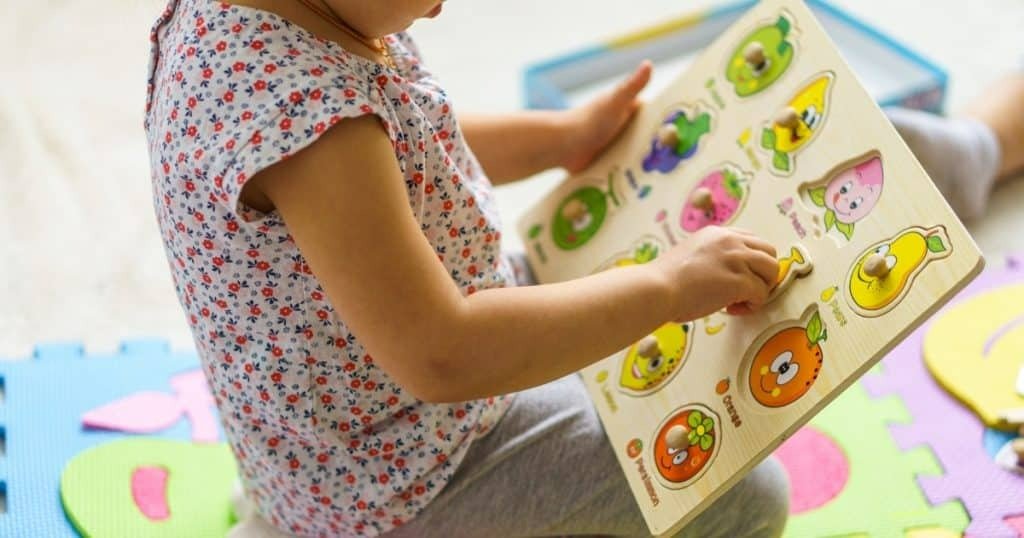 Child developing cognitive and fine motor coordination with wooden fruit puzzle